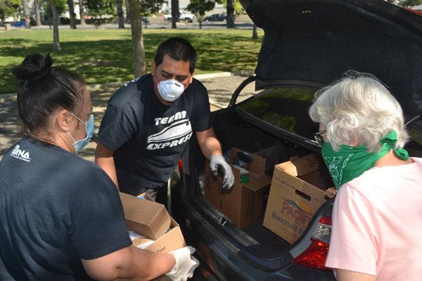 Rob Isquierdo (center) and volunteers help load groceries into a car Friday morning during KCAO's food distribution in Lemoore's Heritage Park.